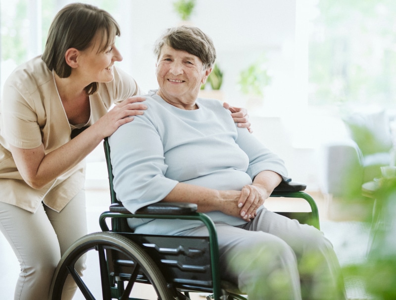 woman standing behind a woman seated in a wheelchair