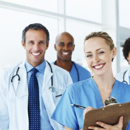 smiling woman with clipboard standing with three smiling medical coworkers in background