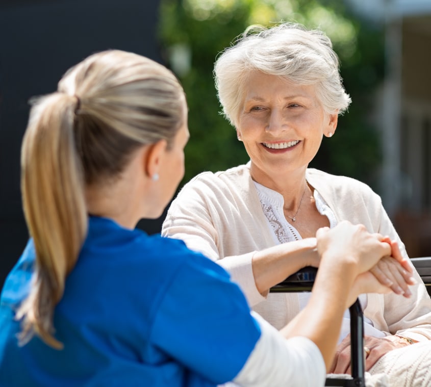 a nurse in blue scrubs talking with a patient outdoors