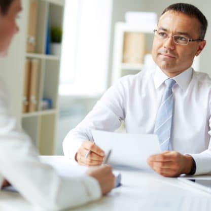 two men sitting at an office table discussing a document