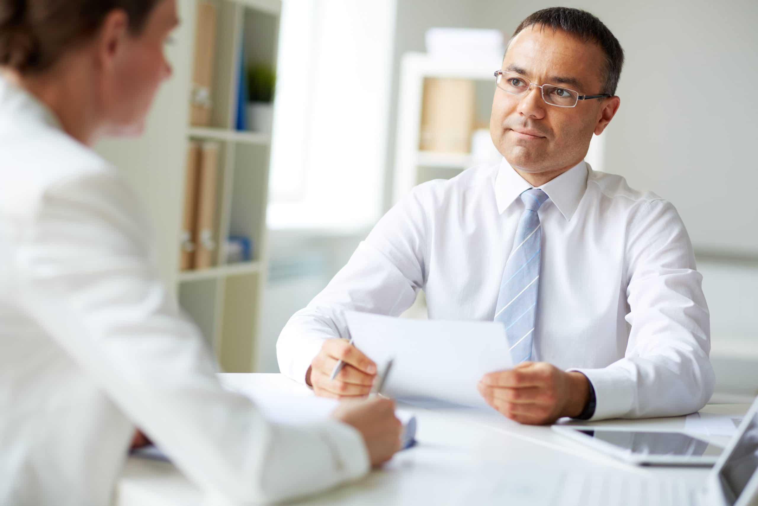 two men sitting at an office table discussing a document