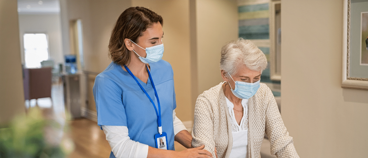 Elderly woman and assisted living center worker walk down hallway