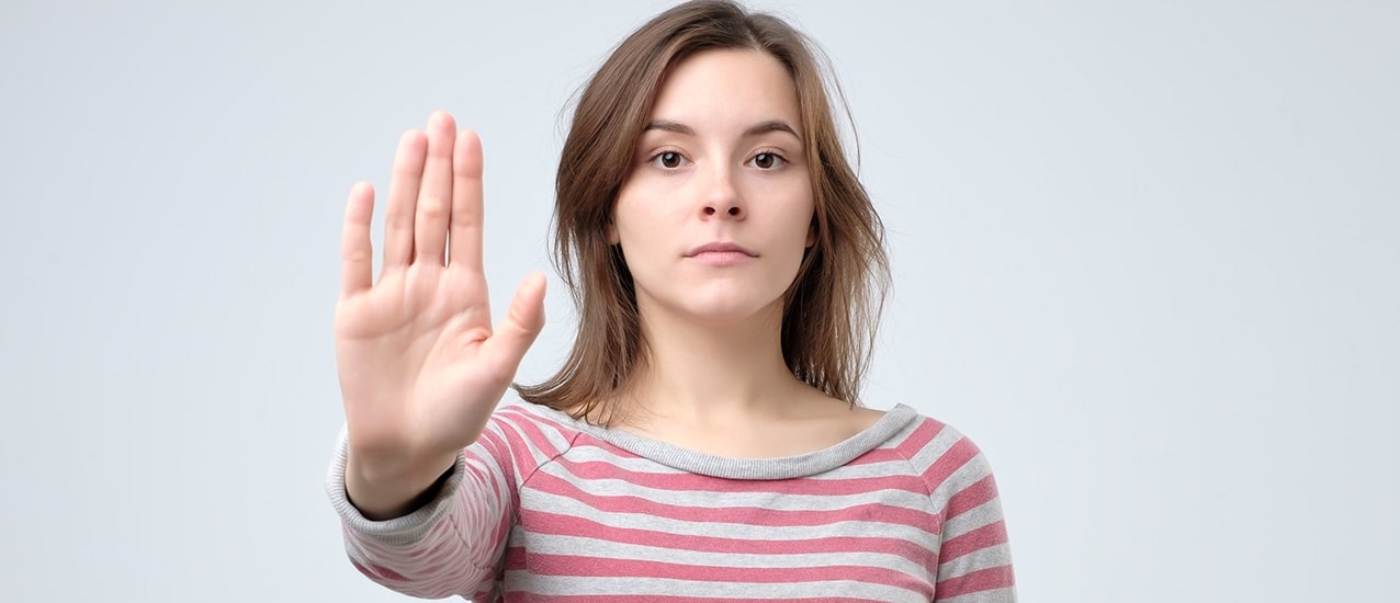 Young woman hand signaling halt with an extended right arm.